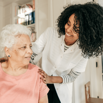 An elderly woman with a caretaker behind her