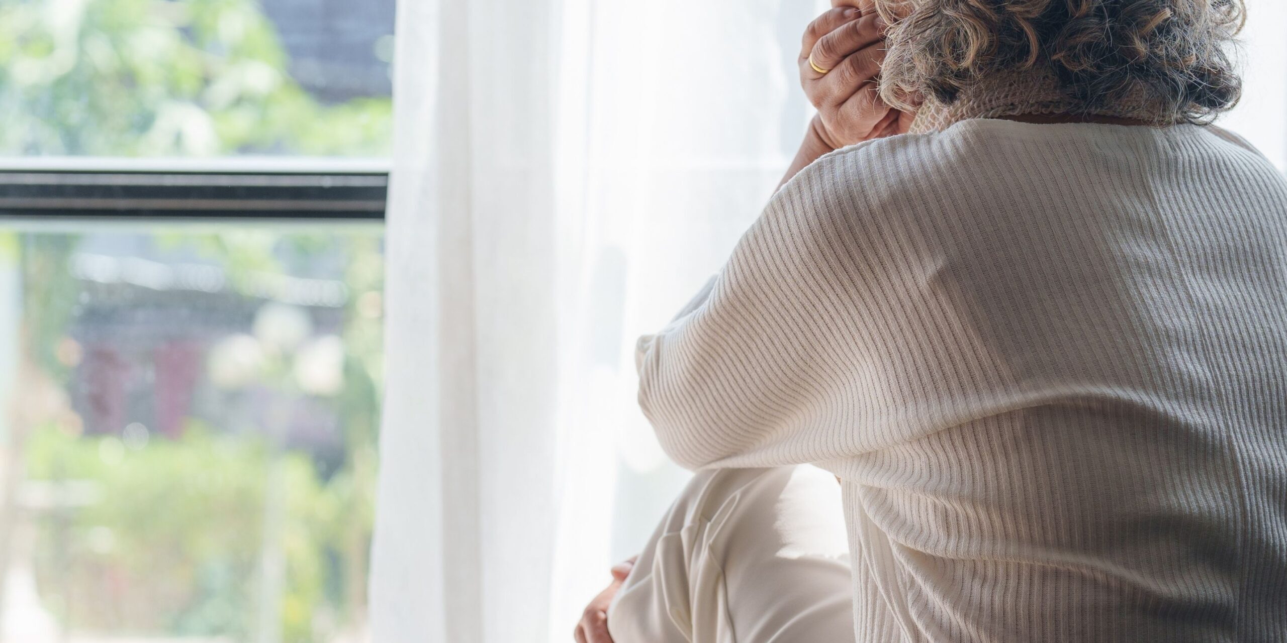 Elderly woman sad looking out window